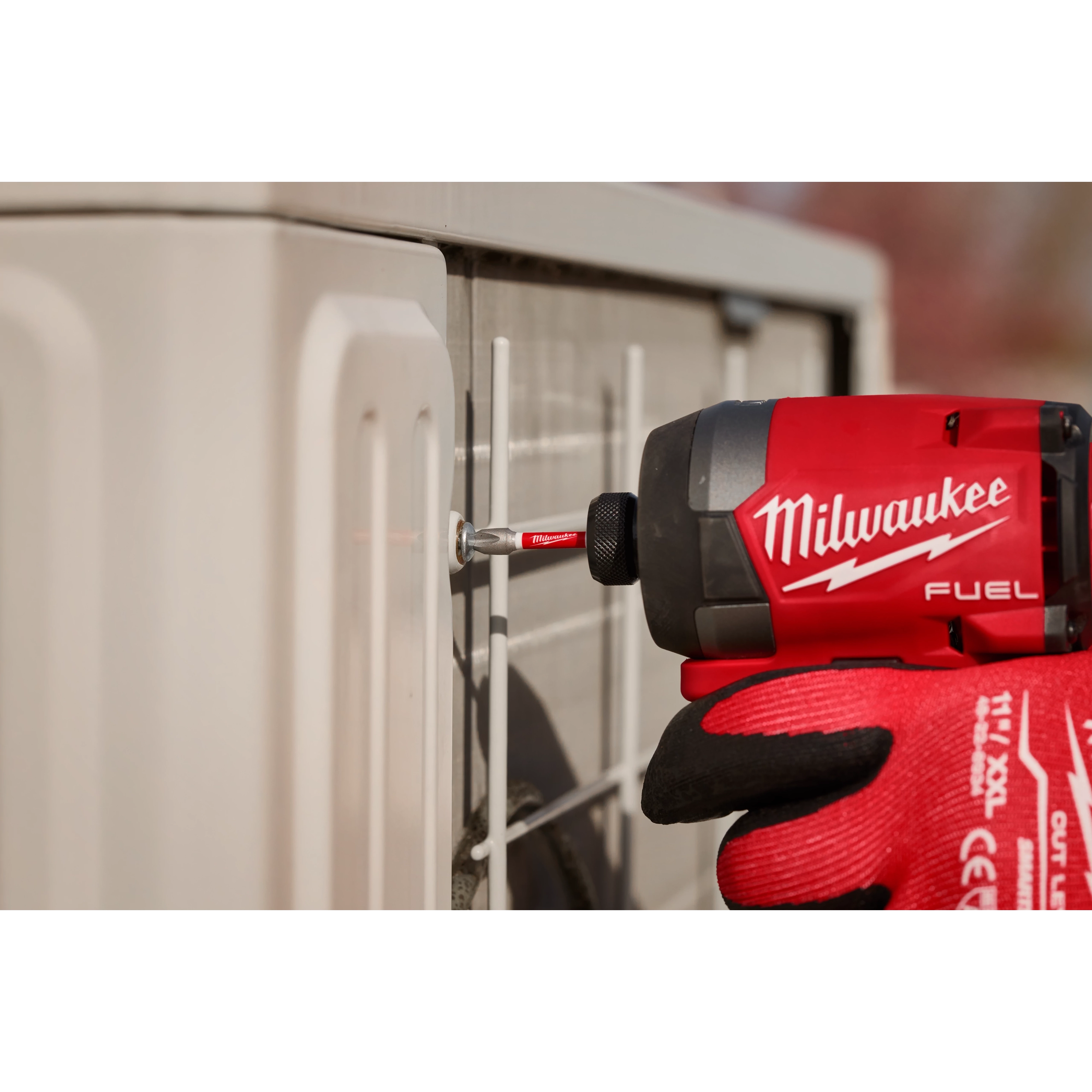 Milwaukee M18 FUEL impact driver with SHOCKWAVE bit driving a screw into a cabinet panel