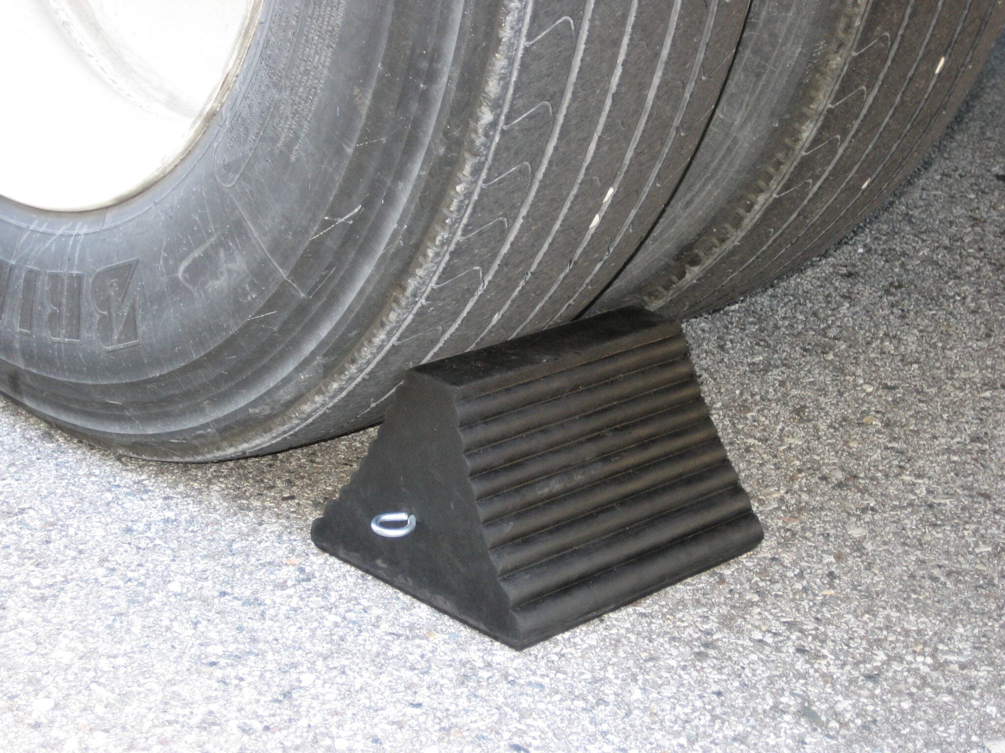 AME International 15300 Rubber Wheel Chock in use against large truck tire on pavement
