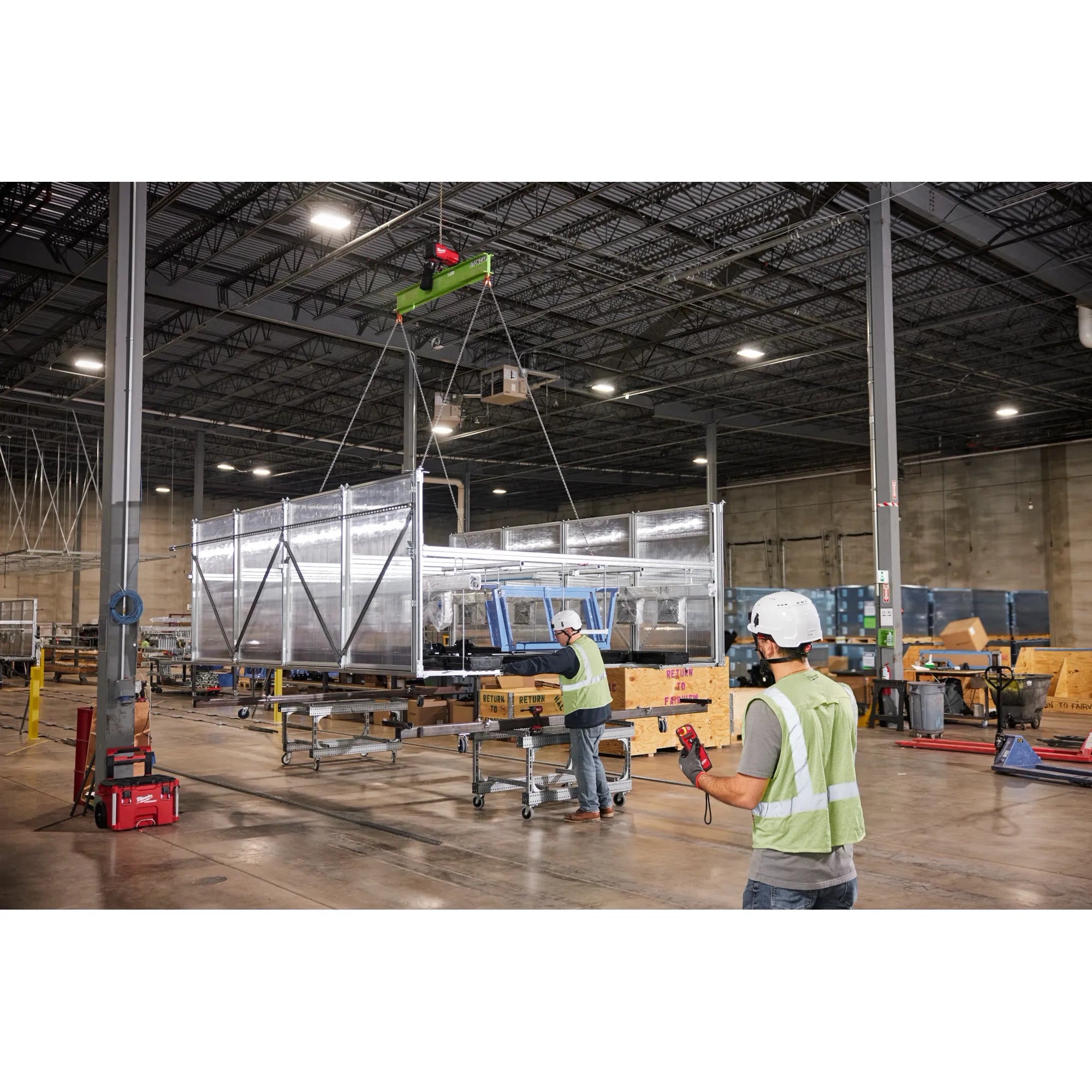 Workers using Milwaukee M18 Chain Hoist with wireless remote to hoist large prefabricated wall section in warehouse