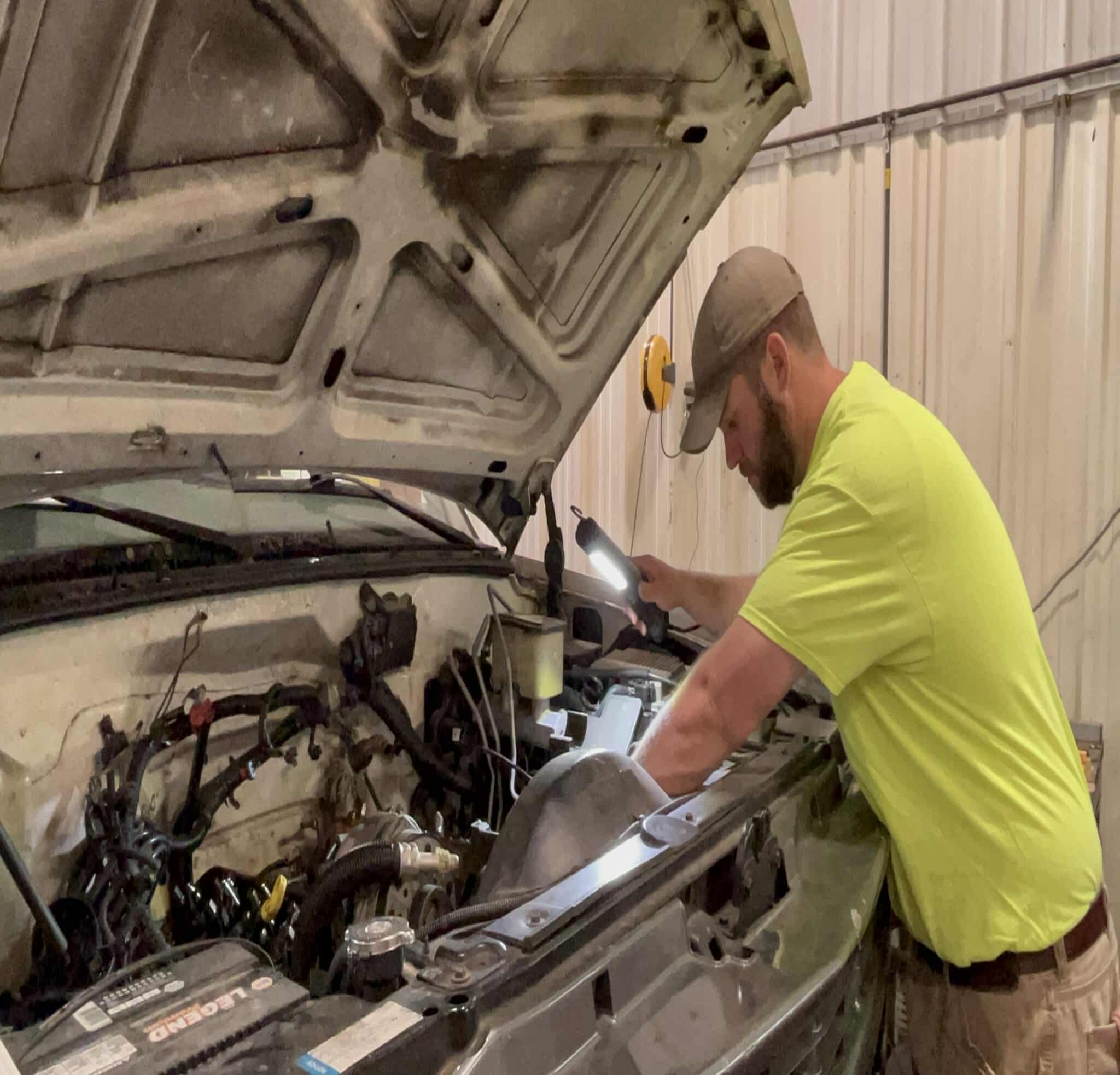 Mechanic using Alert Stamping 5050CL8 ProReel LED work light while working under a vehicle hood