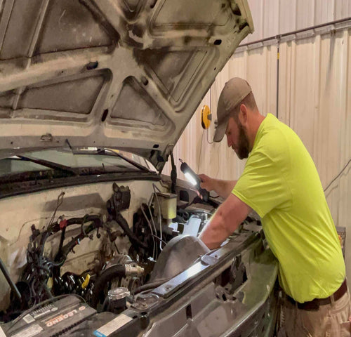 Mechanic using Alert Stamping 5050CL8 ProReel LED work light while working under a vehicle hood