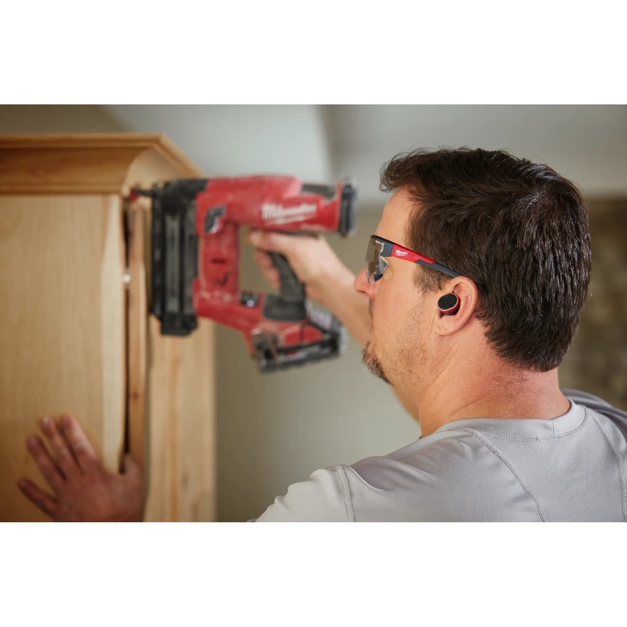 Worker on jobsite wearing Milwaukee REDLITHIUM USB Bluetooth Jobsite Earbuds with foam ear tips