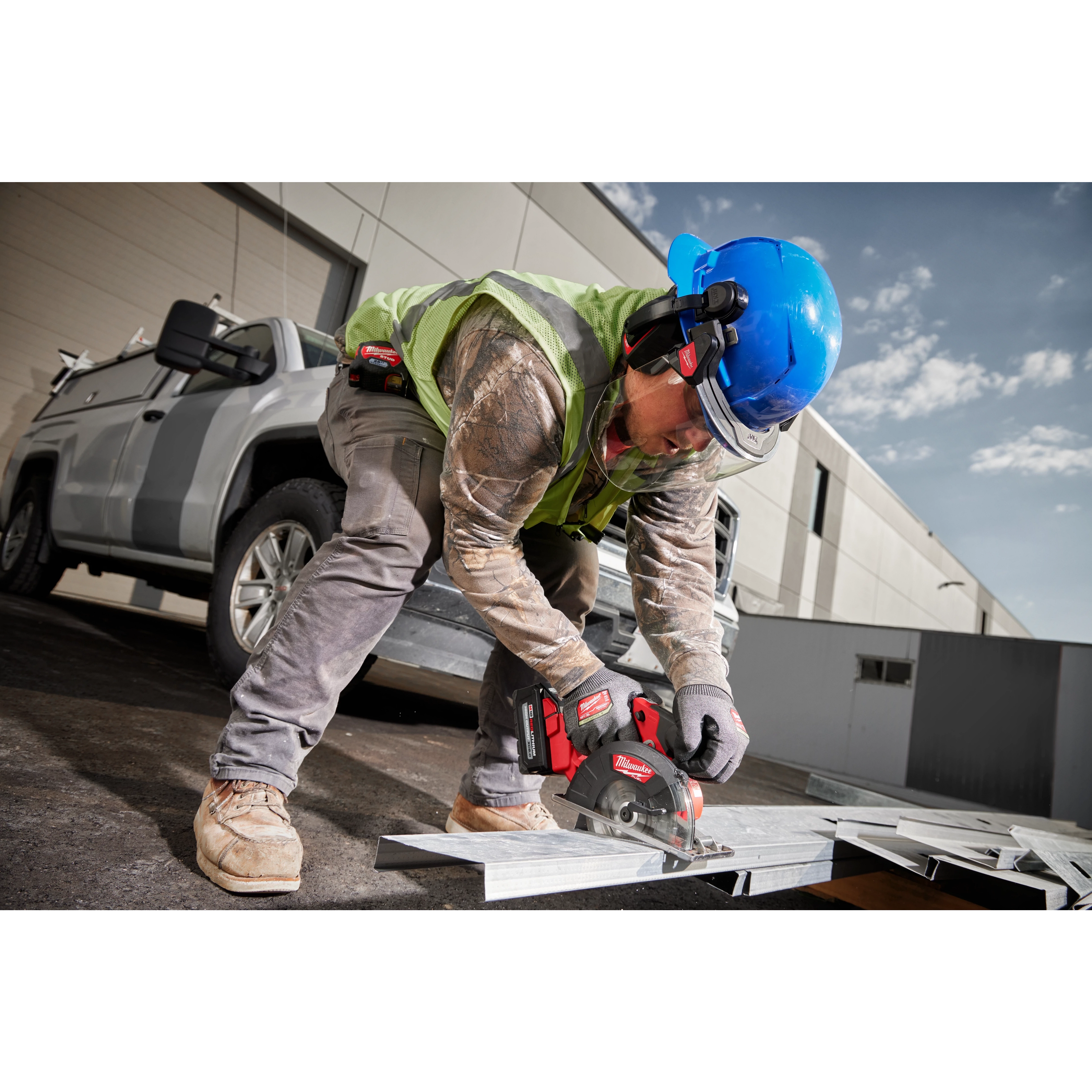 Worker wearing Milwaukee BOLT 26dB Earmuffs on safety helmet while operating circular saw on jobsite