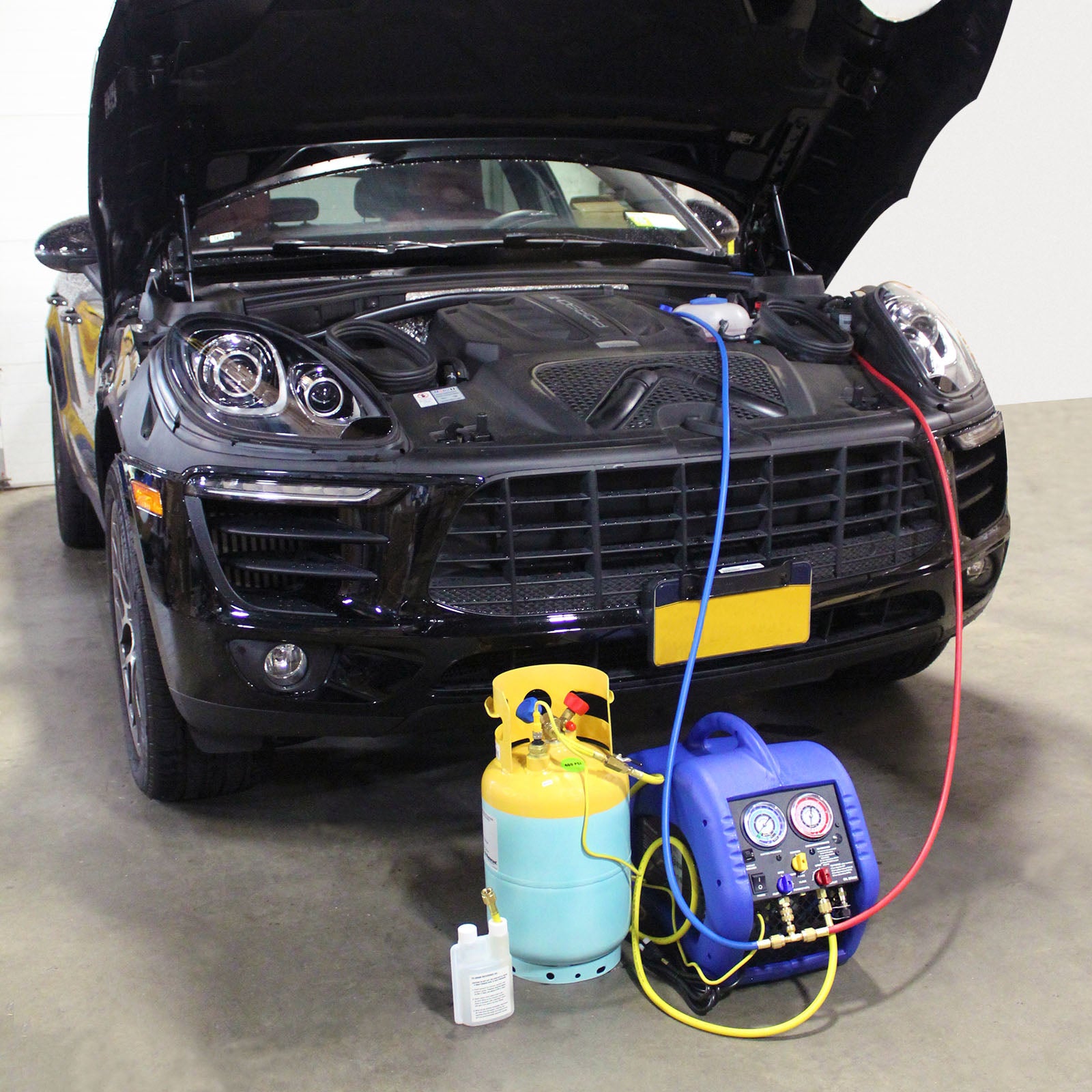 Mastercool 69110 Automotive A/C Recovery System in use connected to a vehicle engine bay with recovery tank and hoses