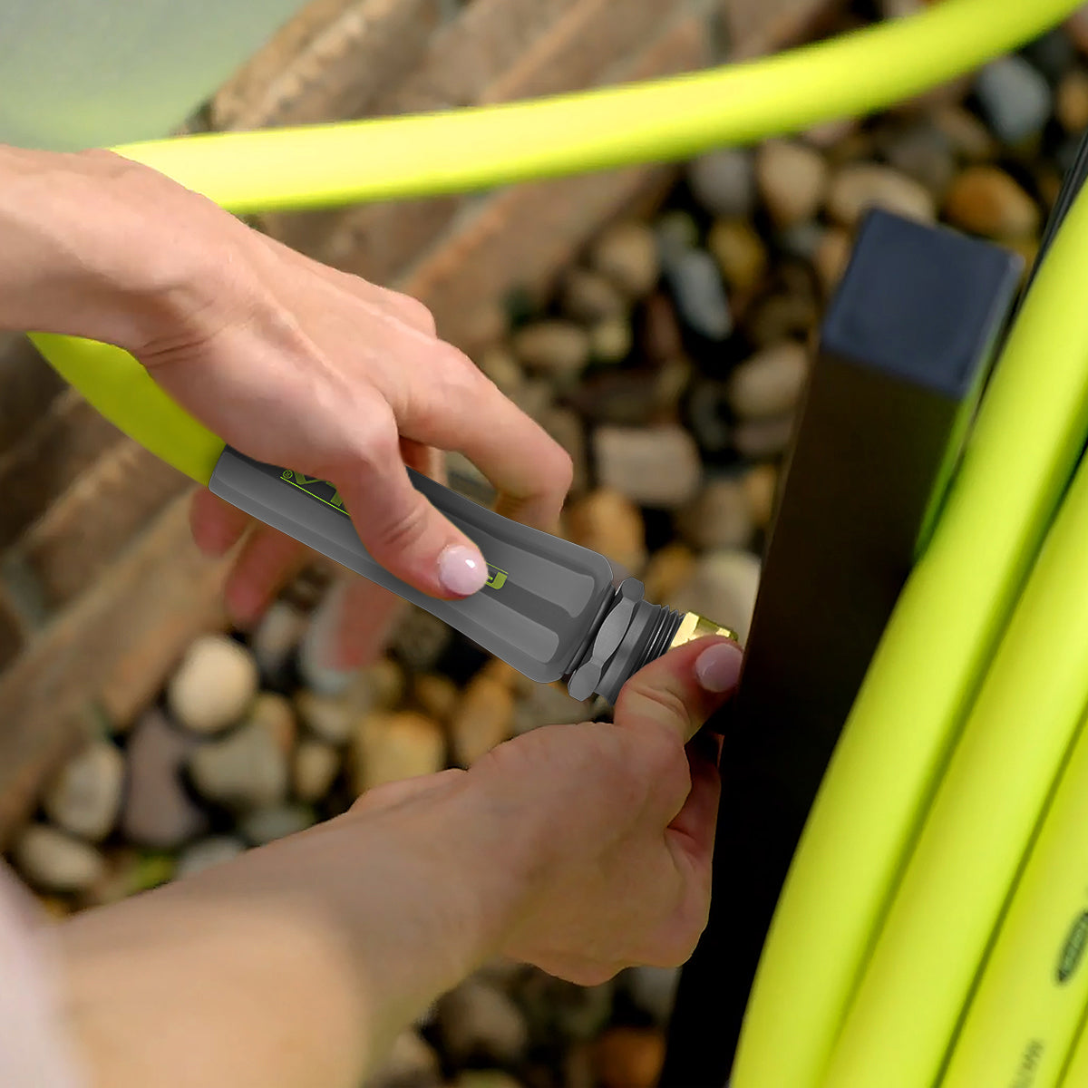 Close-up lifestyle shot of hands connecting Flexzilla Garden Hose fitting to spigot