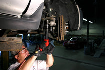 Mechanic using air hammer with retaining spring fitted under vehicle