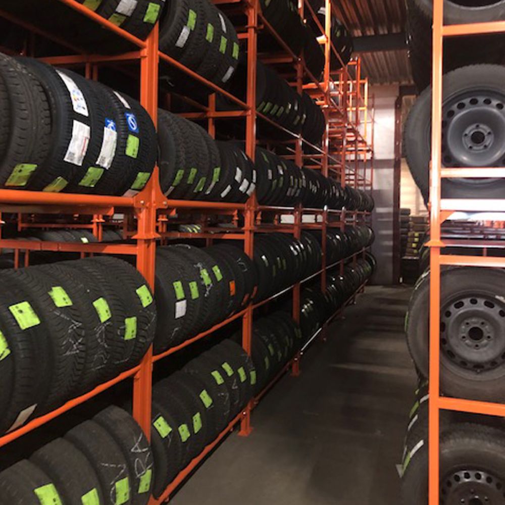 Martins Industries MLTFD Folding Tire Racks in warehouse use, rows of stacked passenger and light truck tires on orange racks