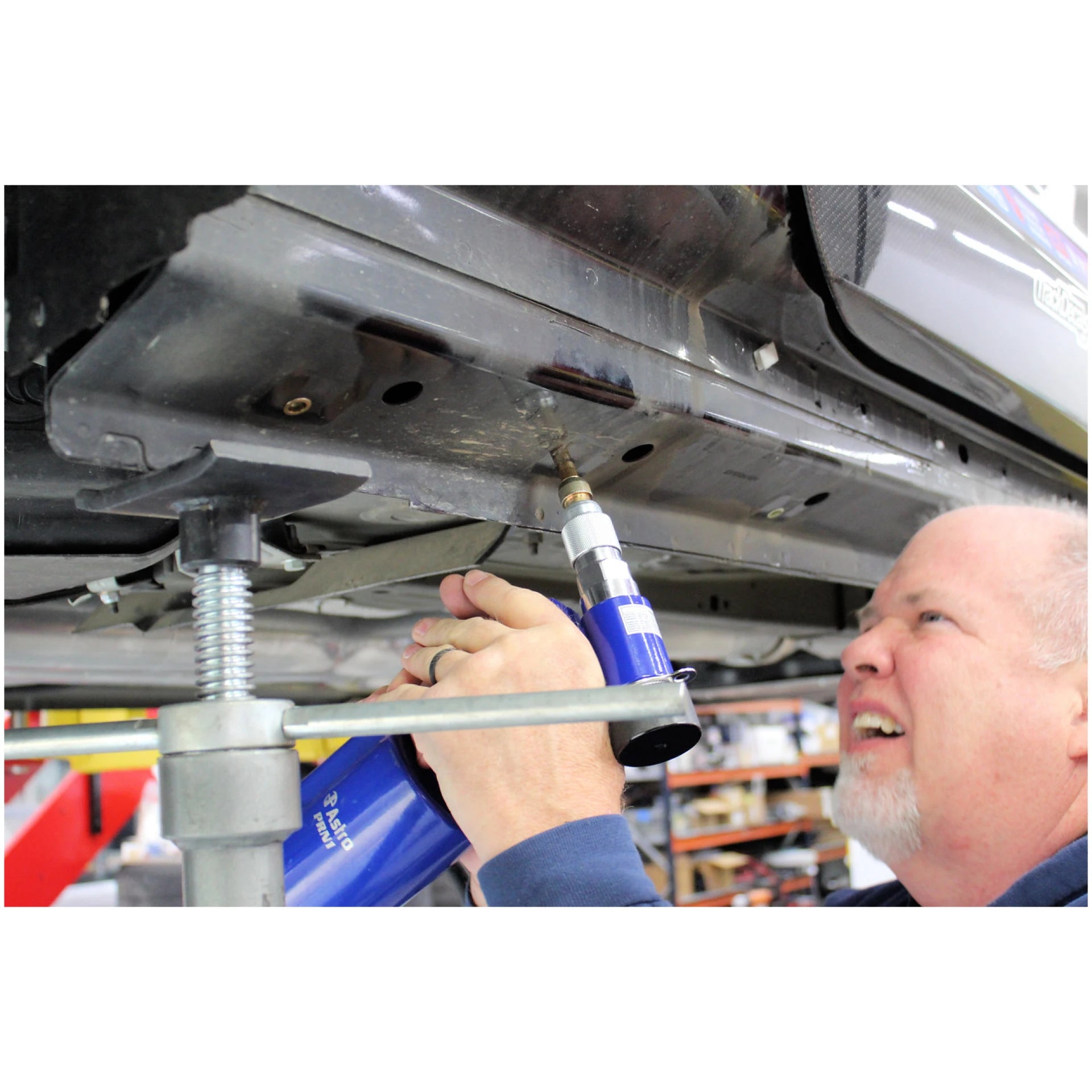 Astro Pneumatic PRN1 pneumatic rivet nut setter in use on vehicle undercarriage close-up view
