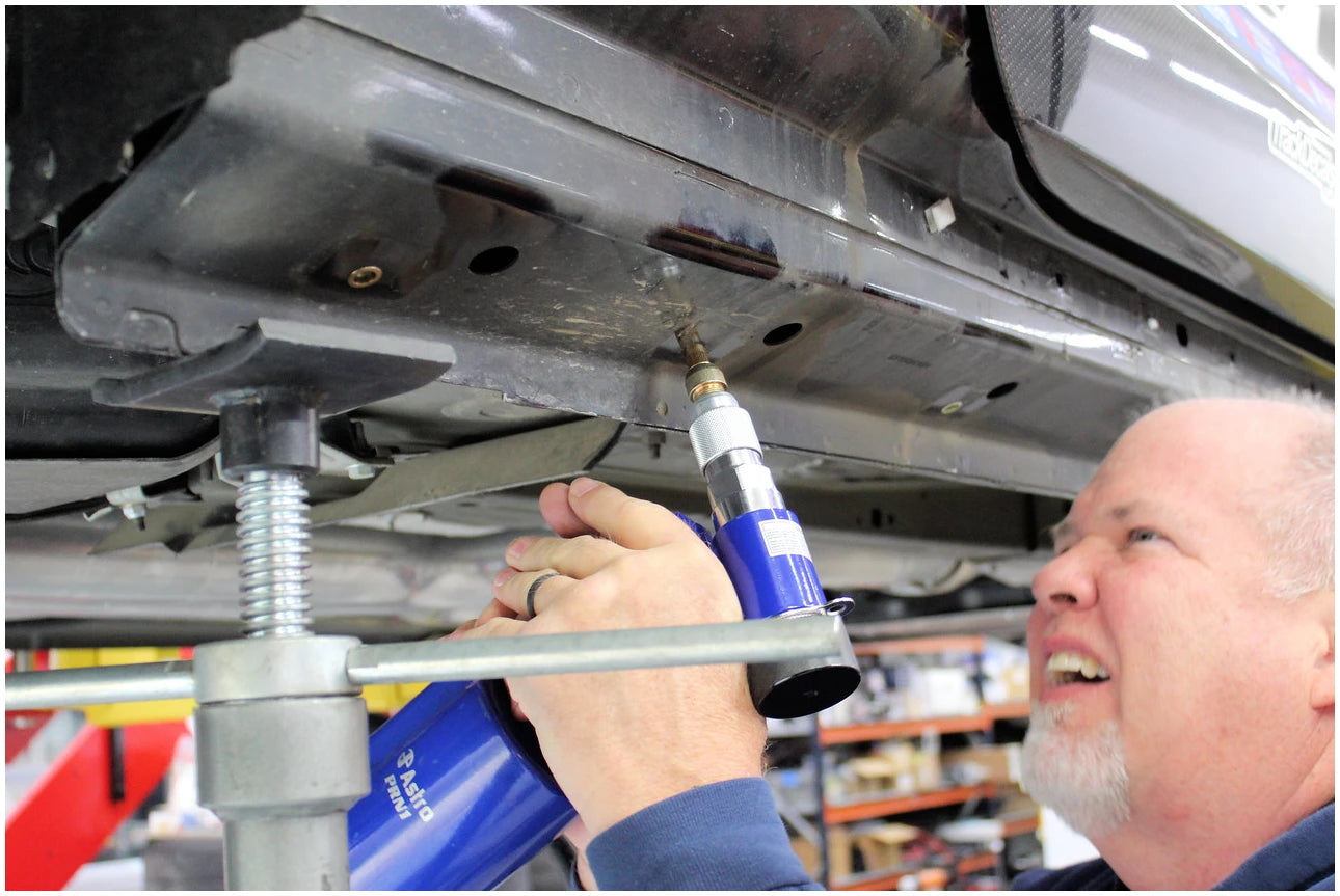 Astro Pneumatic PRN1 pneumatic rivet nut setter being used on vehicle undercarriage in shop