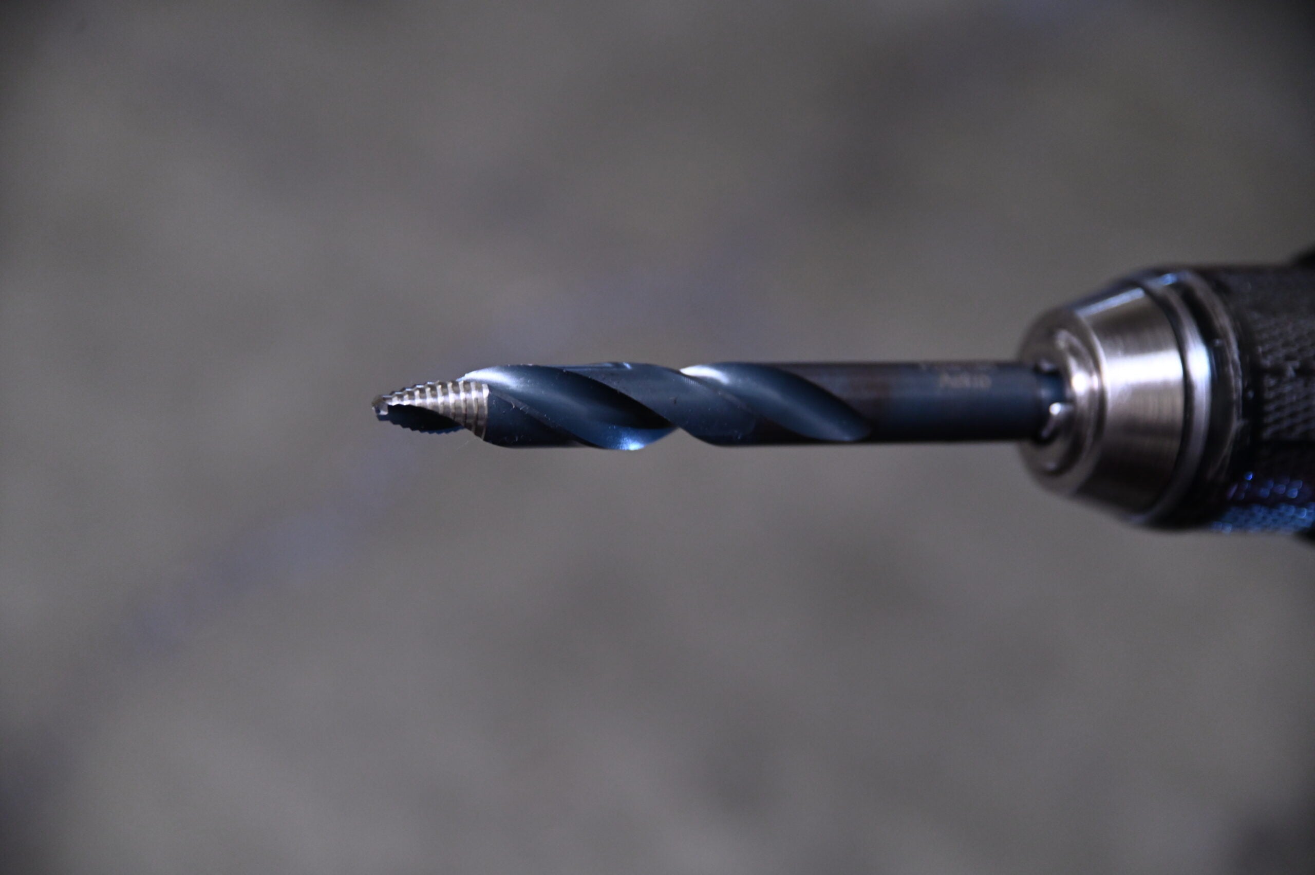 Close-up of Astro Pneumatic TS21 TurboStep HSS drill bit showing spiral fluted stepped tip in drill chuck