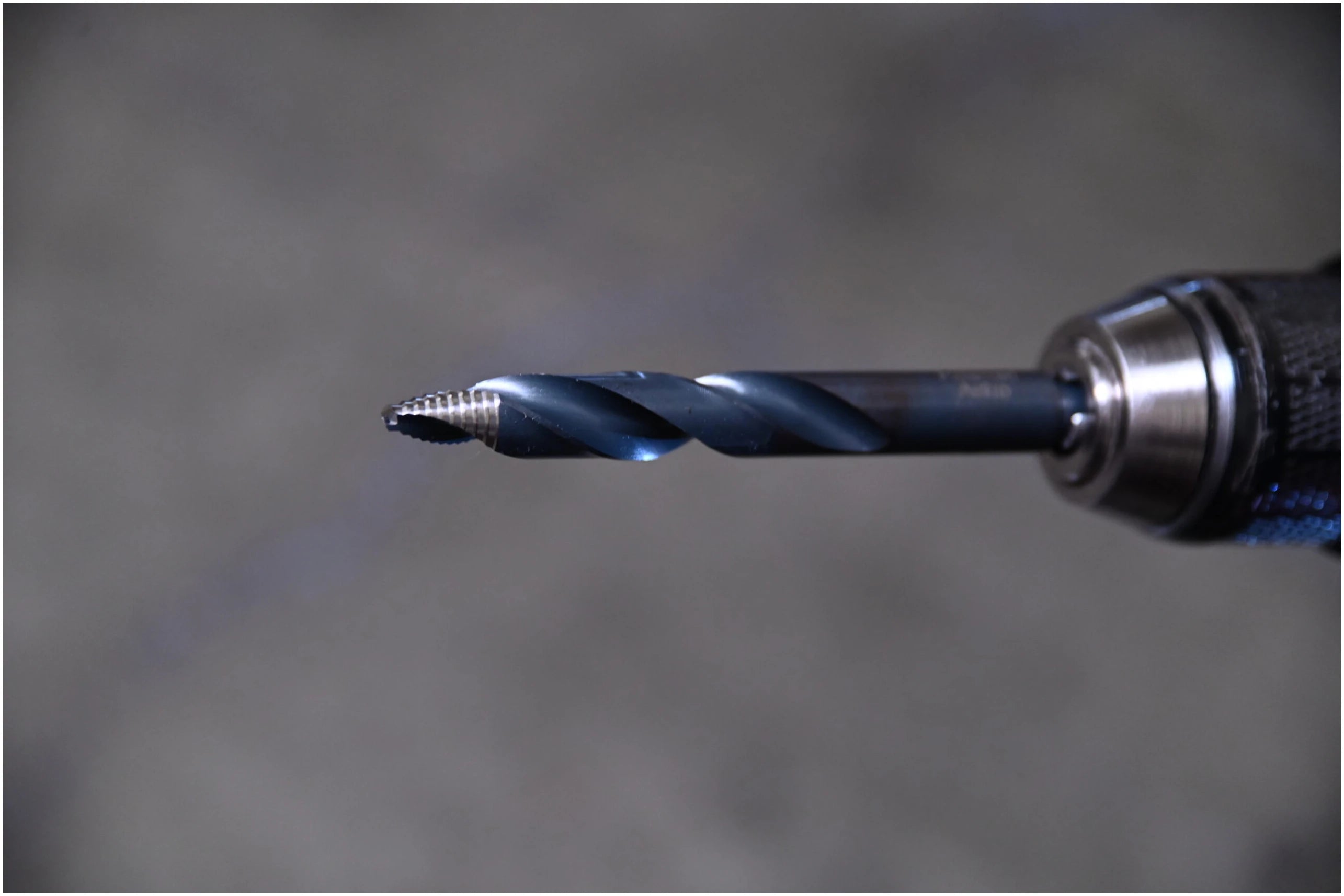 Close-up of Astro Pneumatic TurboStep spiral fluted drill bit showing stepped tip in chuck