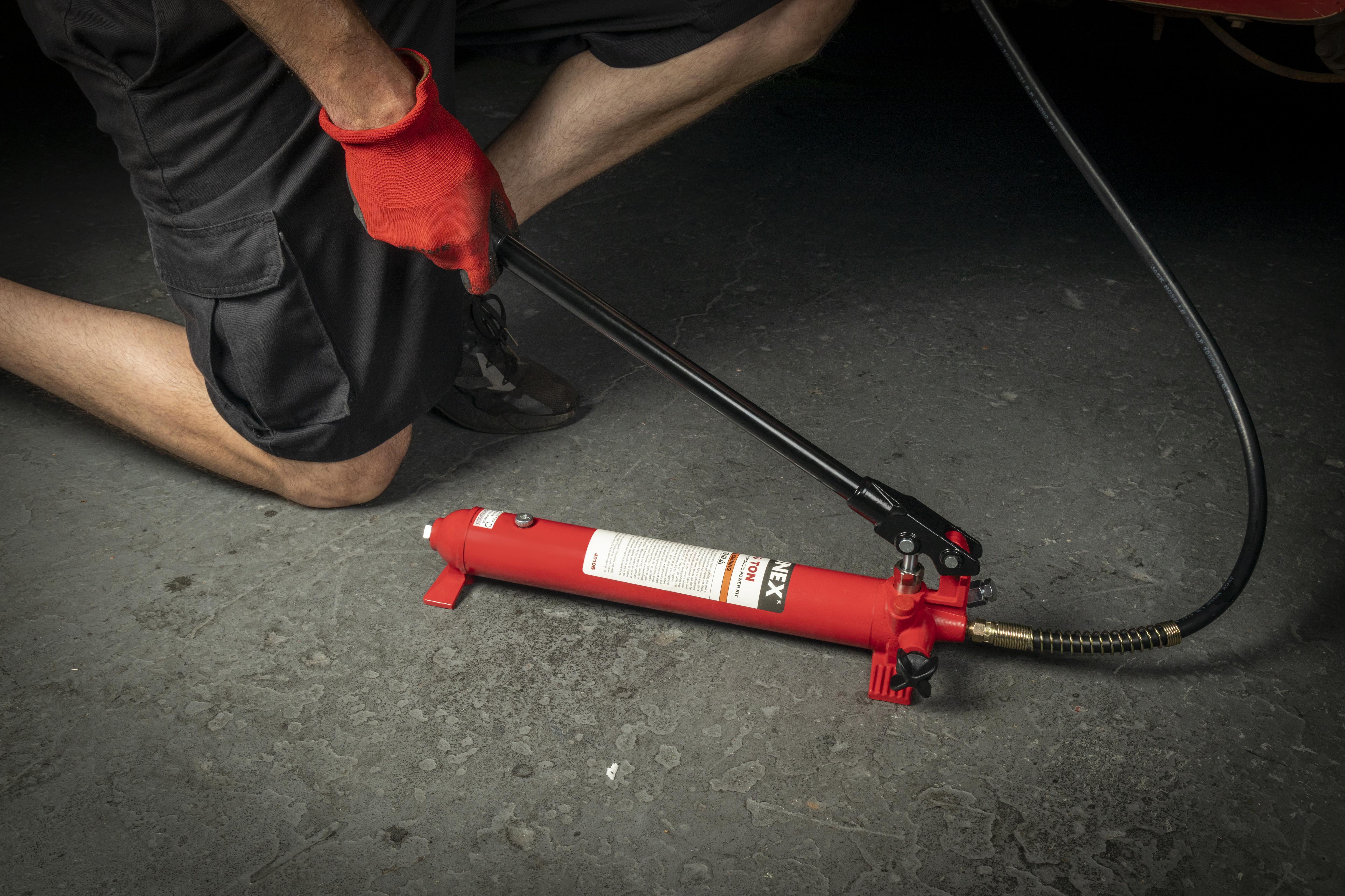 Sunex Tools 4910B hydraulic hand pump with hose being operated on garage floor