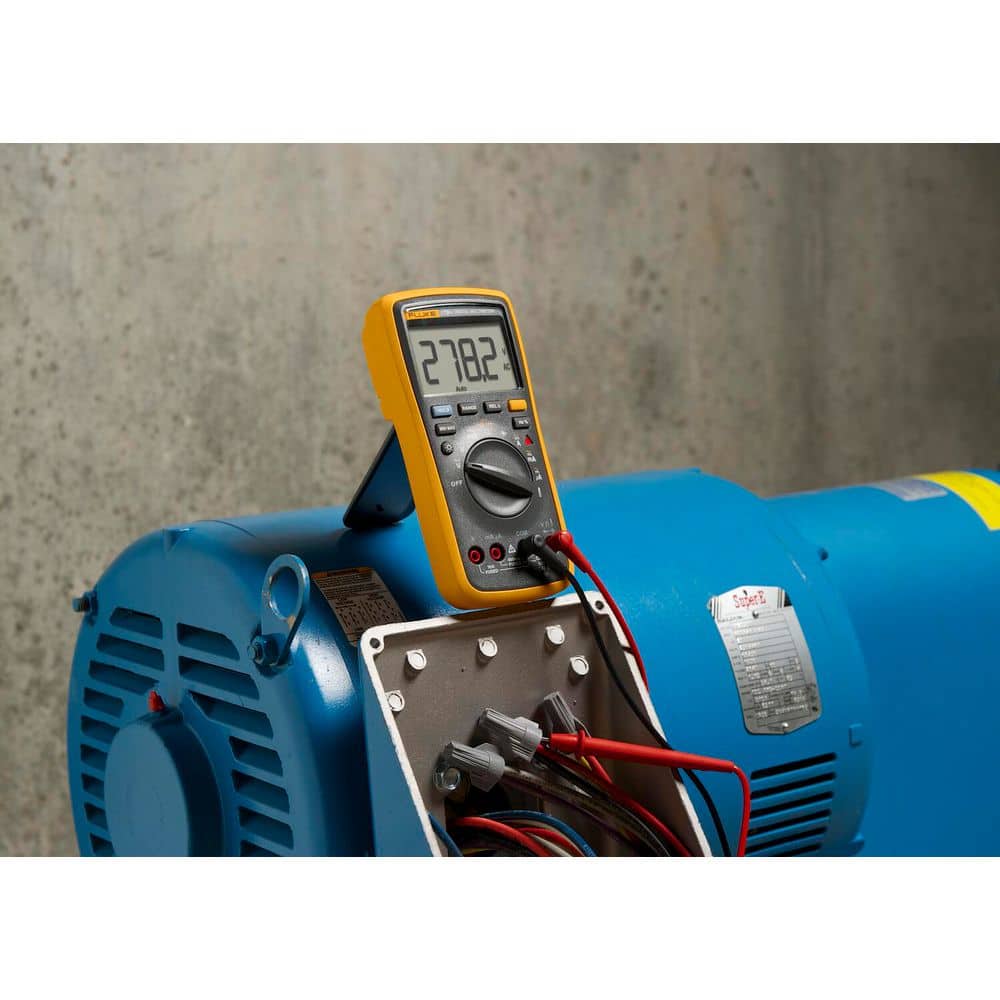Fluke 17B+ Digital Multimeter propped on industrial motor measuring AC voltage