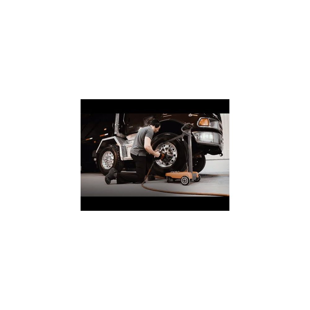 Technician using Martins Industries Impact Boom mobile impact wrench holder while servicing truck tires in a garage