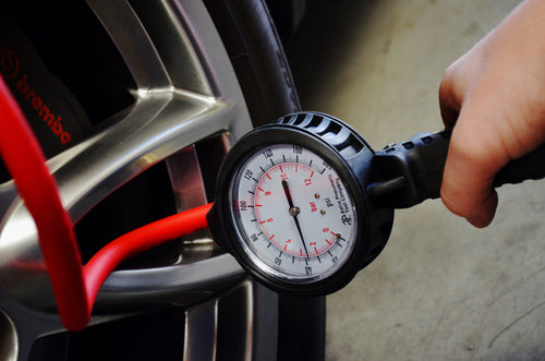 Astro Pneumatic AST-3081 Dial Gauge Tire Inflator in use measuring tire pressure on a performance car wheel