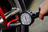 Astro Pneumatic AST-3081 Dial Gauge Tire Inflator in use measuring tire pressure on a performance car wheel