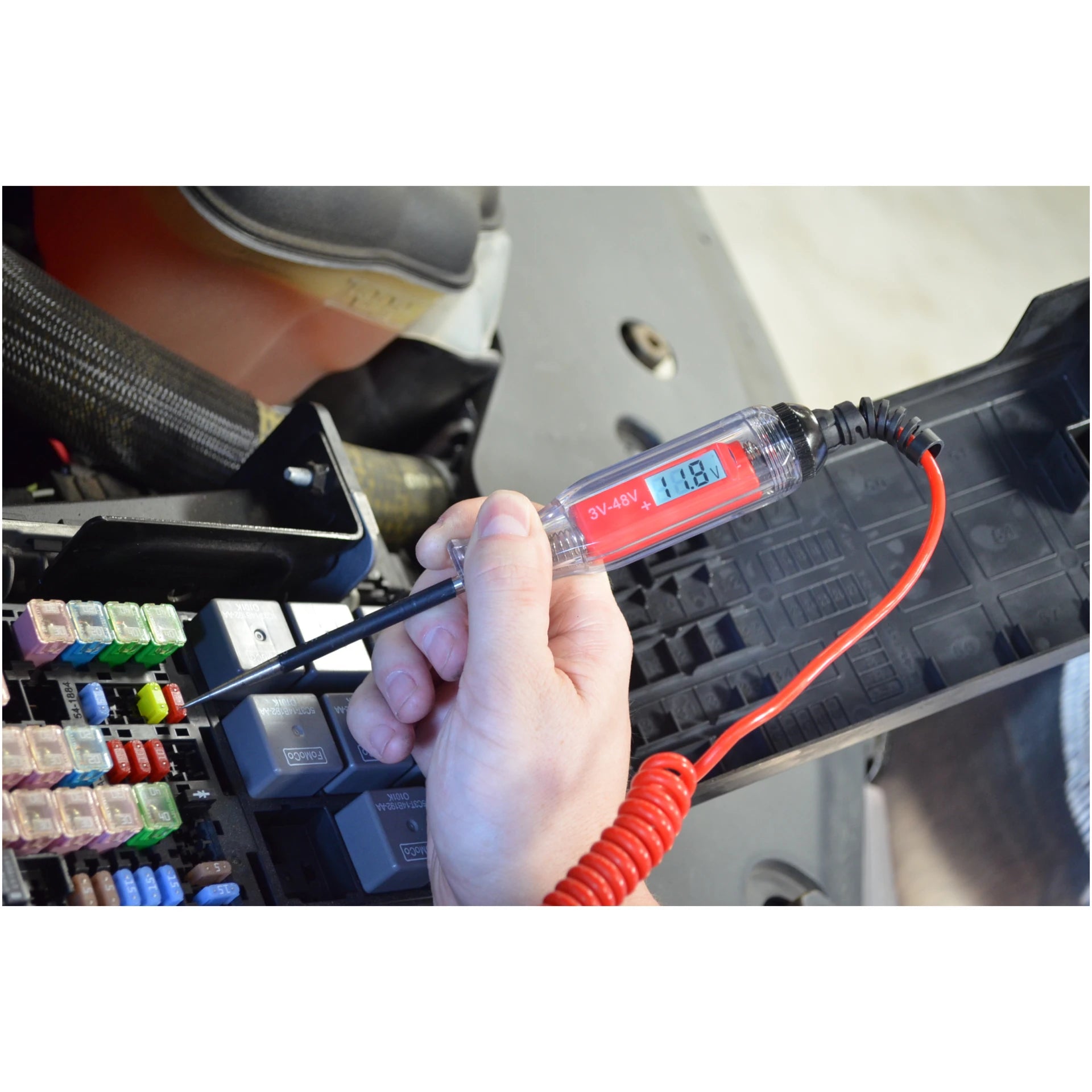 Astro Pneumatic AST-7764 circuit tester testing vehicle fuse box with 11.8V displayed on backlit LCD