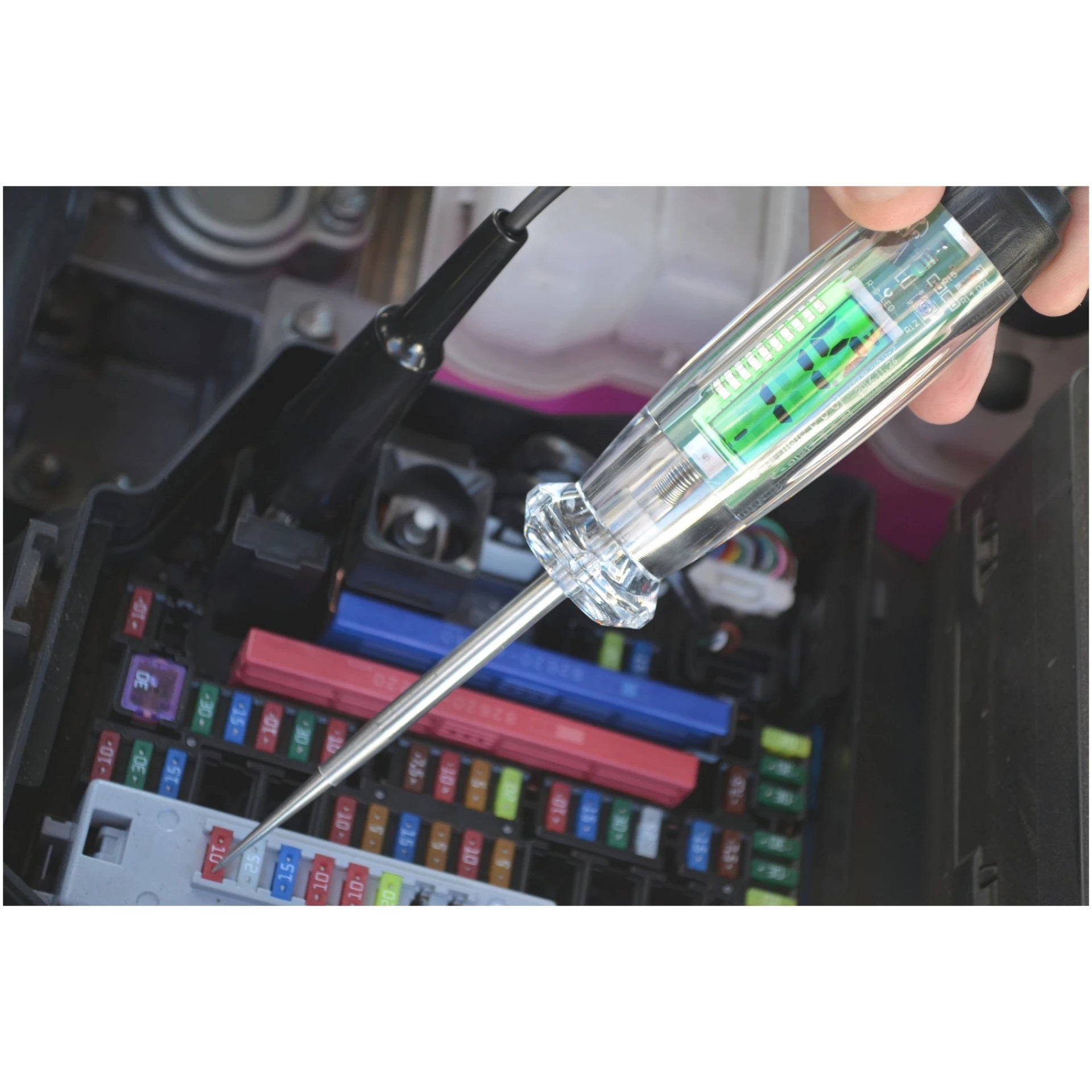 Astro Pneumatic 7767 Digital LCD Circuit Tester probing vehicle fuse box, lifestyle shot