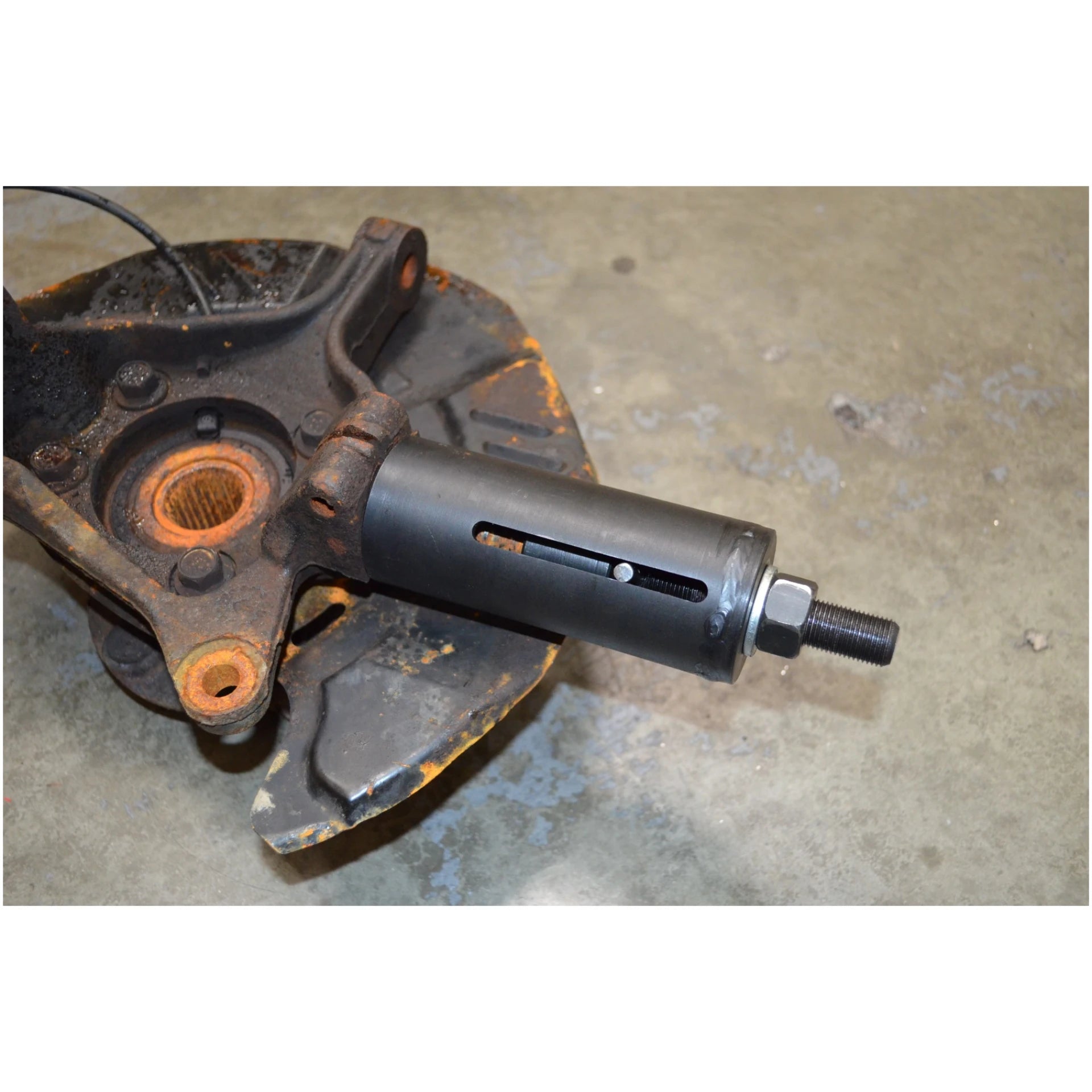Astro Pneumatic 78620 ball joint puller seated in rusted Subaru knuckle assembly during use