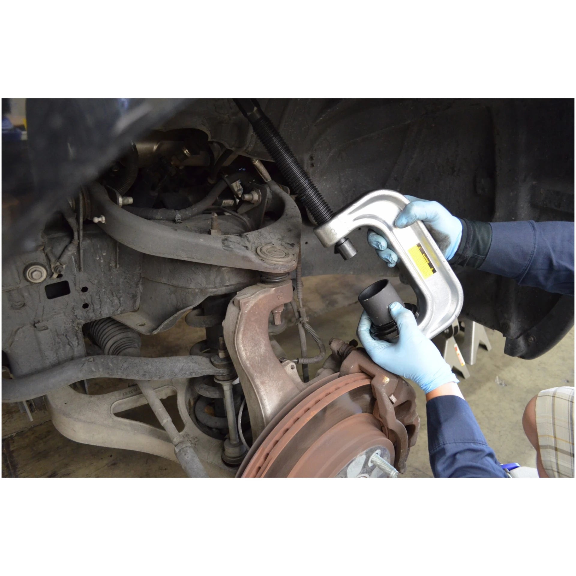 Mechanic using Astro Pneumatic AST-7868 ball joint adapter set on vehicle undercarriage