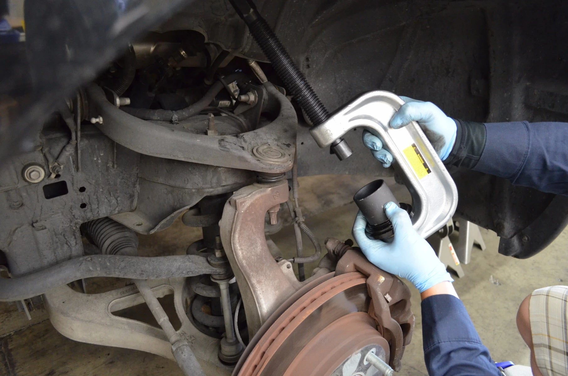 Mechanic using Astro Pneumatic AST-7868 ball joint adapter on vehicle suspension
