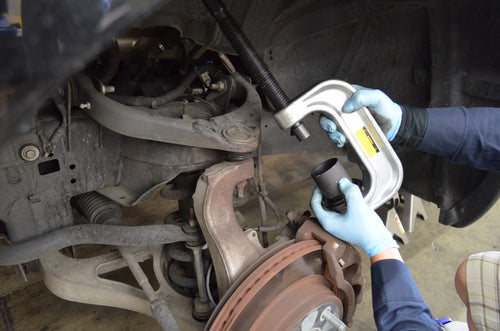 Mechanic using Astro Pneumatic AST-7868 ball joint adapter on vehicle suspension