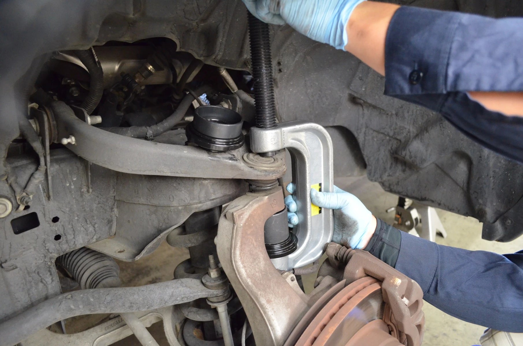 Mechanic using Astro Pneumatic 7897 ball joint C-frame press on vehicle suspension