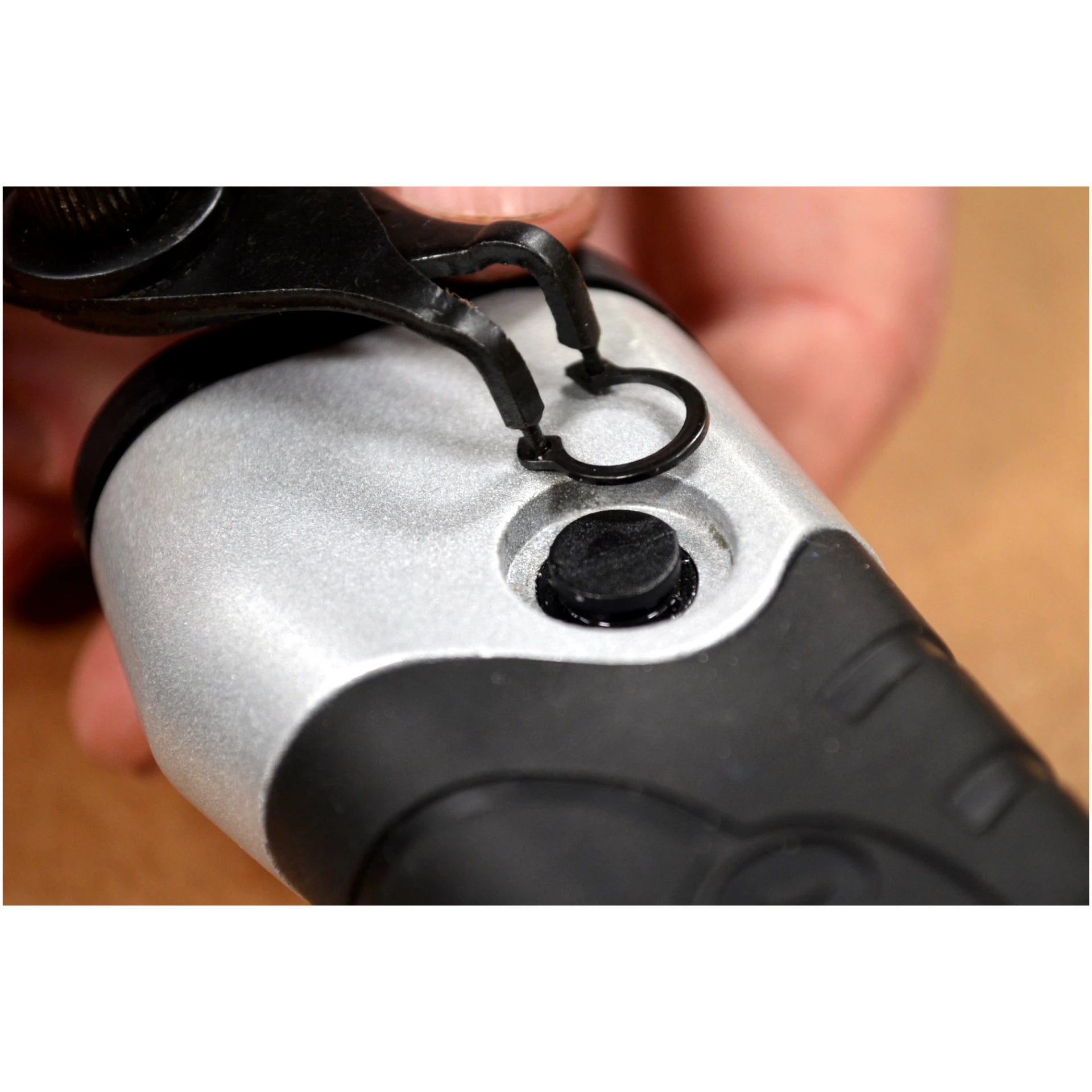 Close-up of snap ring pliers removing an internal snap ring from a tool component